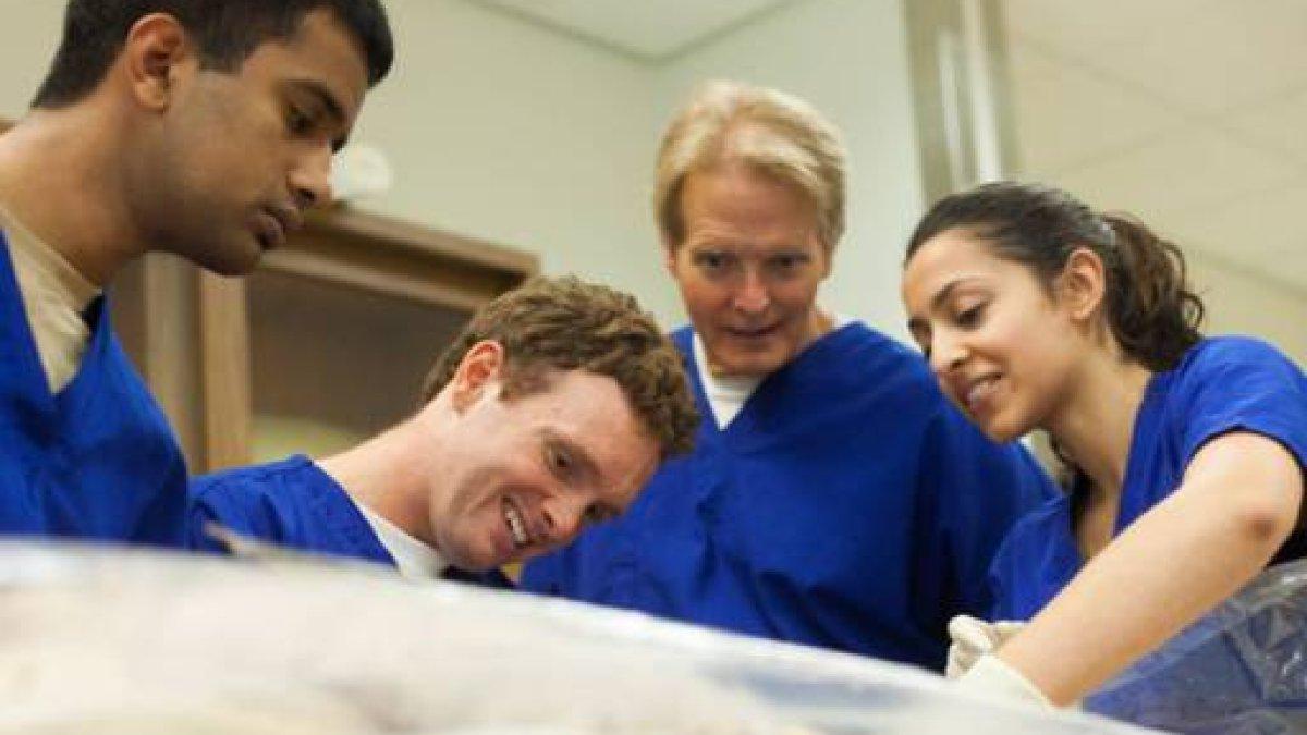 three students and professor wearing scrubs in classroom